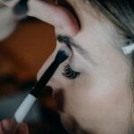 A detailed shot of a woman getting eye makeup applied with precision and artistry.